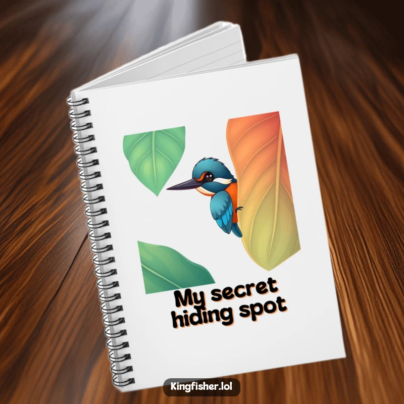 Front cover of a notebook featuring a funny cheerful kingfisher bird peeking from behind a large, colorful leaf, a great funny gift.